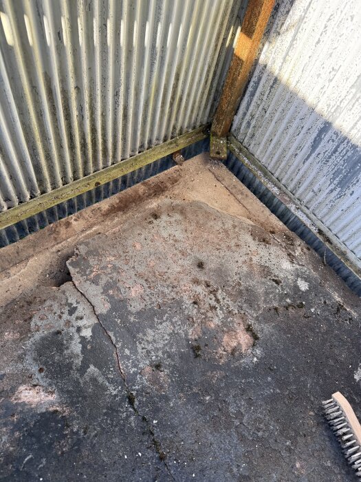 Sliten och sprucken balkongyta med rostiga metallrör och fuktskadade väggar, del av en renoveringsplan för fransk balkong.