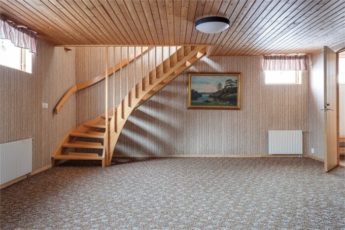 Gillestuga från 1980-talet med trätak, trappa, målad vägg och radiatorer. Bilden visar retro inredningsstil.