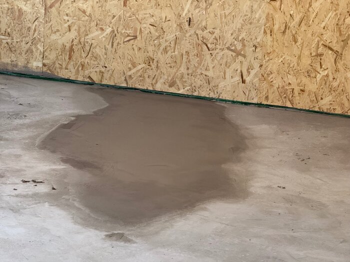 Området där golvet har jämnats ut och flytspackel har applicerats, med en OSB-skiva i bakgrunden.