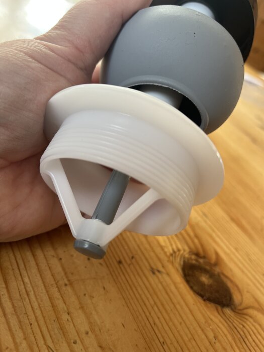 Ny spolmekanism för toalettcistern visas med fokus på plastdetaljer och grå gummidel.