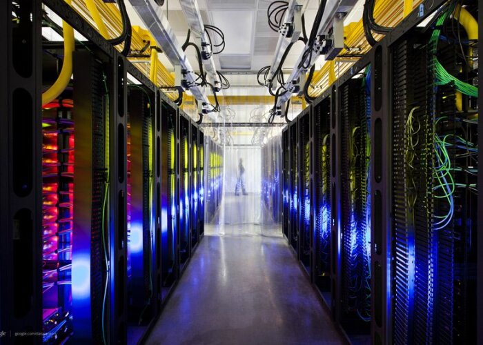 Rader av serverrack med olika typer av kablage och belysning i ett serverrum.