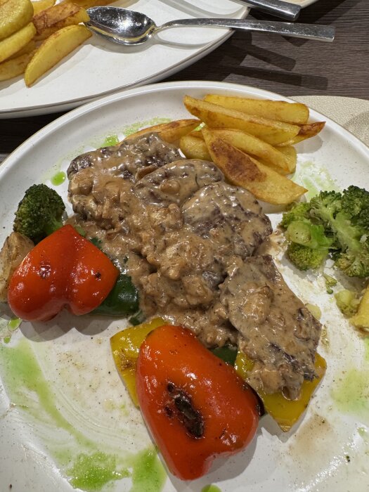 Tallrik med medaljonger i valnötssås, grillad paprika, broccoli och klyftpotatis i Yerevan, Armenien.