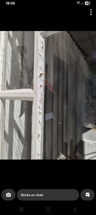 Fönster med flagad färg; visar resultatet av tidigare renovering med tydligt slitage, särskilt längs kanterna på fönsterrutan.