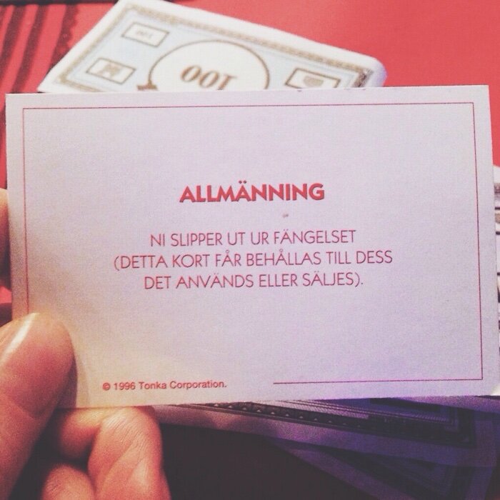 Brädspelskort med texten "ALLMÄNNING: Ni slipper ut ur fängelset" från ett spel med låtsaspengar i bakgrunden.