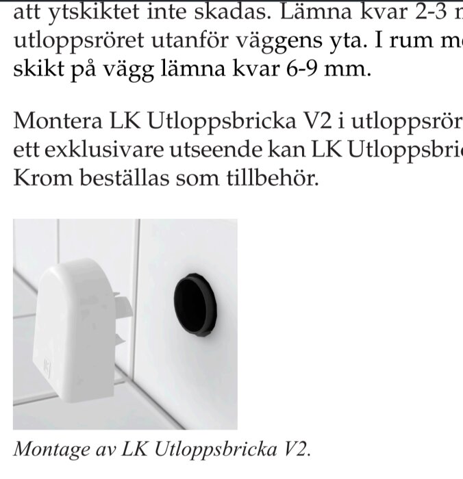 Vit LK Utloppsbricka V2 monterad på en kaklad vägg med ett svart utloppsrör.