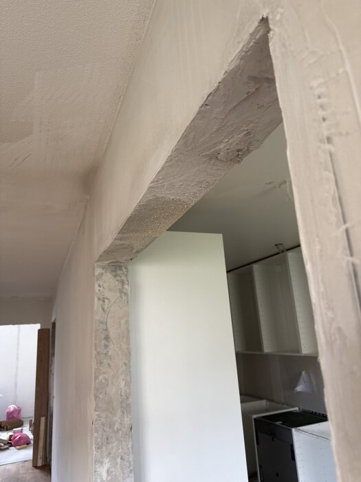 Dörröppning i en betongvägg som behöver jämnas ut innan gipsmontering; fråga om fästmassa för gips på taket, nämner kakelfix.