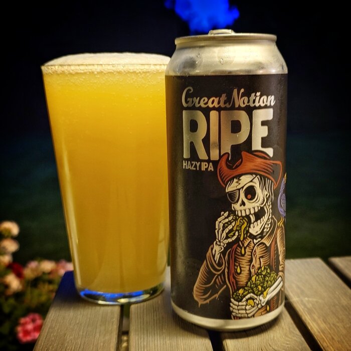 Burk med Great Notion Ripe Hazy IPA och ett glas gyllene öl på ett bord utomhus.
