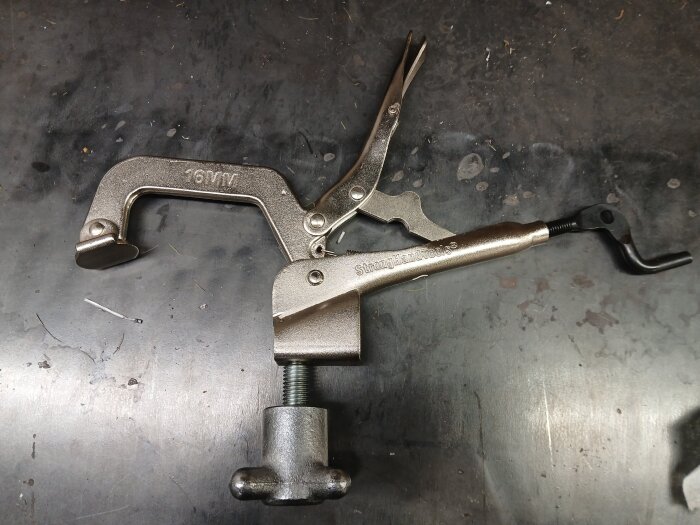 StrongHand bordslåstång med vev monterad på en fot, liggande på en metallbänk. Proof of concept med T-mutter för stabilitet.