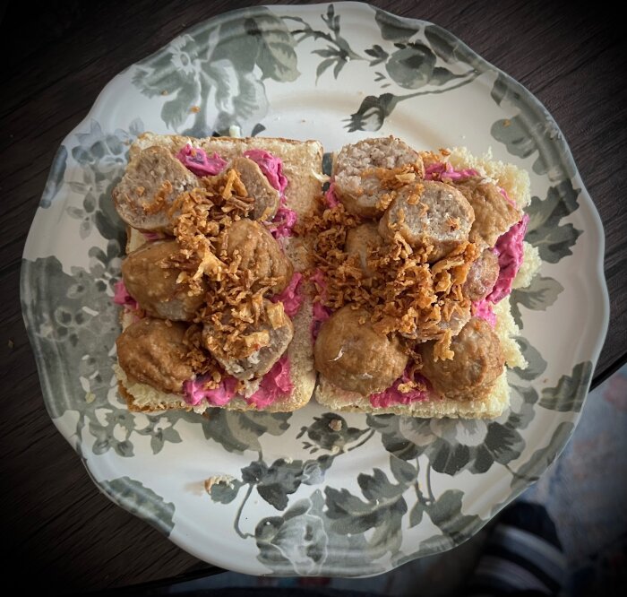 Köttbullsmacka med rödbetssallad och rostad lök på hembakat tekaka-bröd, upplagd på blomsterdekorerad tallrik.