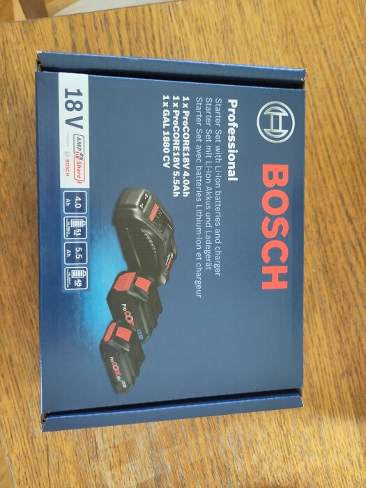 Förpackning av Bosch Professional Li-Ion batteriladdarset, innehållande två ProCore 18V batterier och en laddare, på ett träbord.