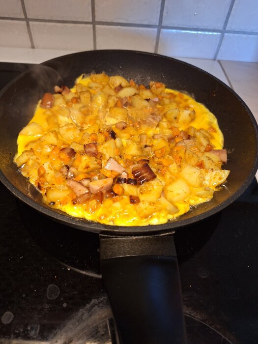 Stekt bondomelett med potatis och lök i en stekpanna på spisen.