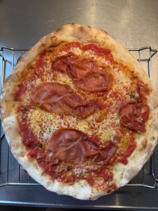 Hemmagjord pizza med tomatsås, ost och skivad skinka på en krispig botten, skapad med ett experimenterat degrecept.