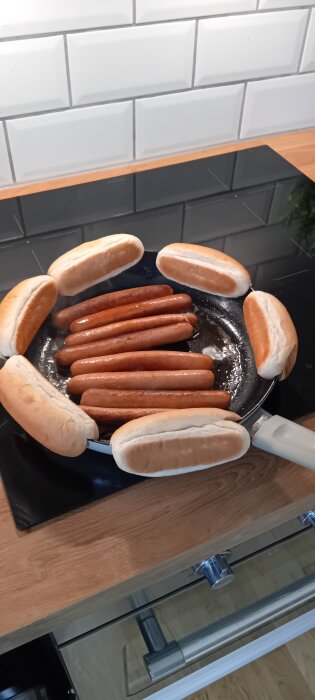 Korv och bröd steks i en panna på en spishäll, lunch med korv och bröd förbereds.