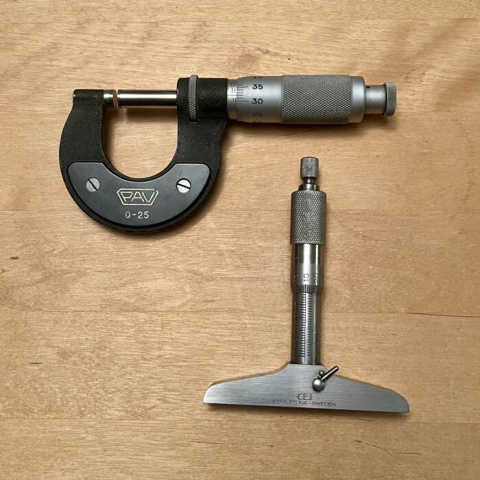 Mikrometer från Präzisions-Apparatebau Vaduz och djupmikrometer från CE Johansson Eskilstuna på ett träbord.