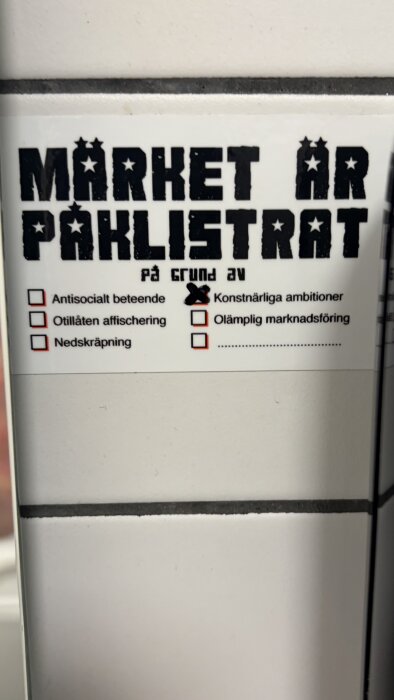 Klistermärke med texten "Märket är påklistrat på grund av" följt av alternativ med en markering på "Konstnärliga ambitioner".