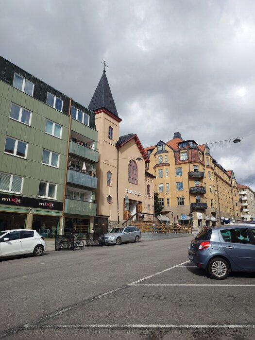En gata med bilar parkerade utanför en byggnad som har en torn-liknande del och skylten "Omnipollo".