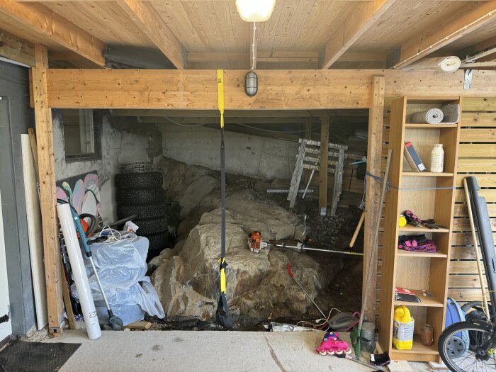 Carport med trädäck, bar jord synlig under; verktyg, redskap och garageförvaring synliga, inklusive däck, hylla, och trädgårdsredskap.
