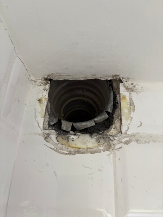Ventilationskanal i ett hustak, delvis täckt av borttaget gips och spackel, med synliga grova kanter och ett rör med Ø100.