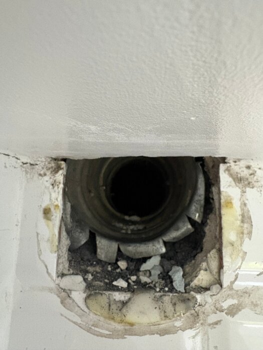 Ventilationskanal delvis täckt av ett undertak, med borttaget gips och spackel. En regel blockerar kanalens topp med cirka 3 cm.