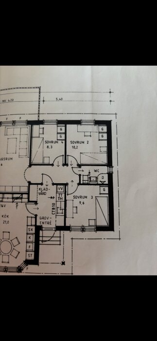 Ritning över ett hus med olika rum markerade, inklusive sovrum och WC, samt dimensioner och markeringar för väggar och dörrar.