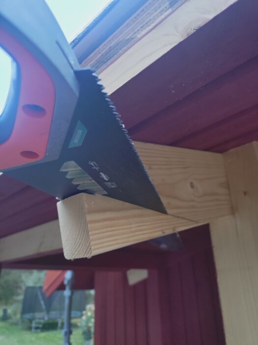 Handsaw cutting wooden beam under a roof, showcasing precise angles and smooth cuts despite overhead work.