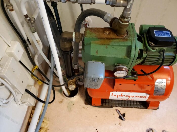 Äldre DAB JET 61 M pump med hydropress installerad, omgiven av rör och kopplingar, del av diskussionsämne om vattenpumpens tryckproblem.
