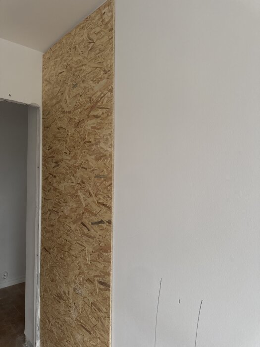 OSB-skiva monterad på vägg av lättbetong, del av projekt för att göra väggen tjockare och få plats med skjutdörr.