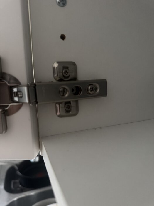 Gångjärn från ett äldre IKEA-kök med monteringshål för dämpare synliga, utan blum-dämpare fastsatt.