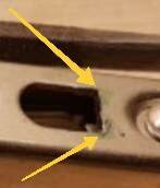 Närbild på ett delvis fyrkantigt hål i metall, markerat med gula pilar, där Dremel och fil kan ha använts för att skapa formen.