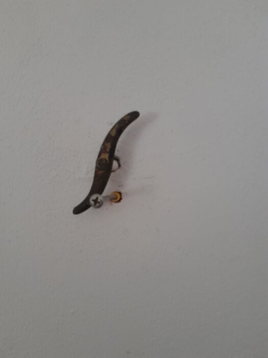 Närbild av ett spjällhandtag monterat på en vägg, som ska tas bort vid installation av en kamin.