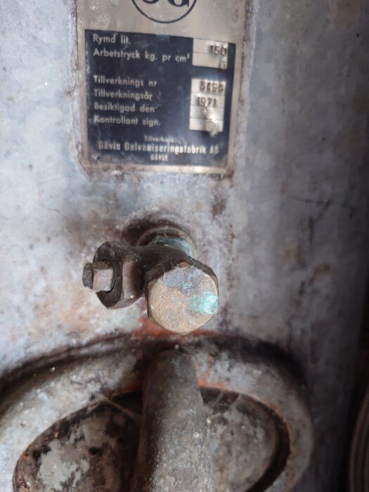 Närbild på ventil med etikett från Gävle Galvaniseringsfabrik AB, specificerar tryck och tillverkningsår 1971, monterad på en gammal hydrofor.