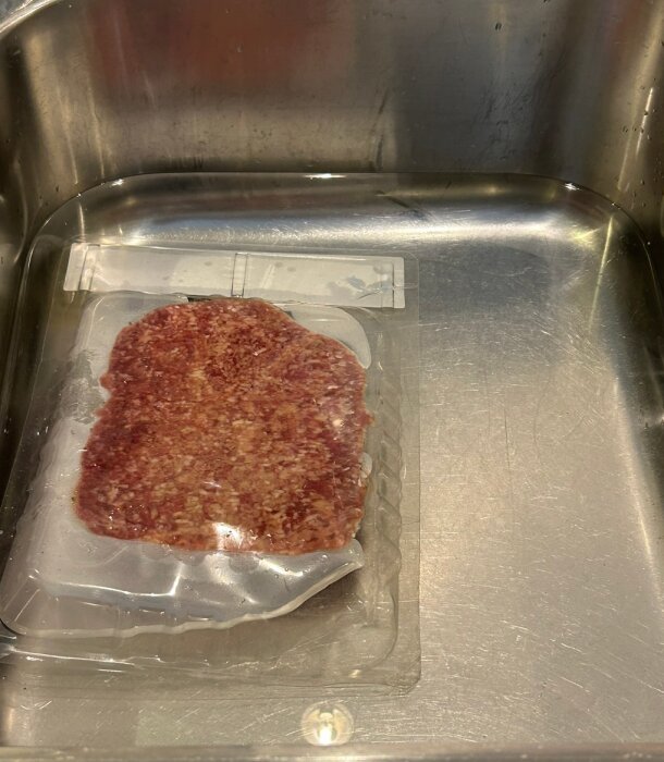 Förpackat kött i plast i en diskho av rostfritt stål.
