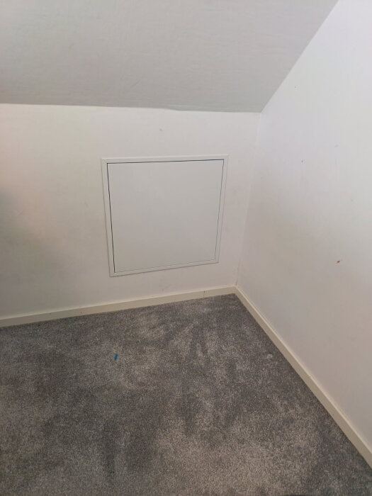 Vit lucka installerad i snedtak ovanför grå matta.