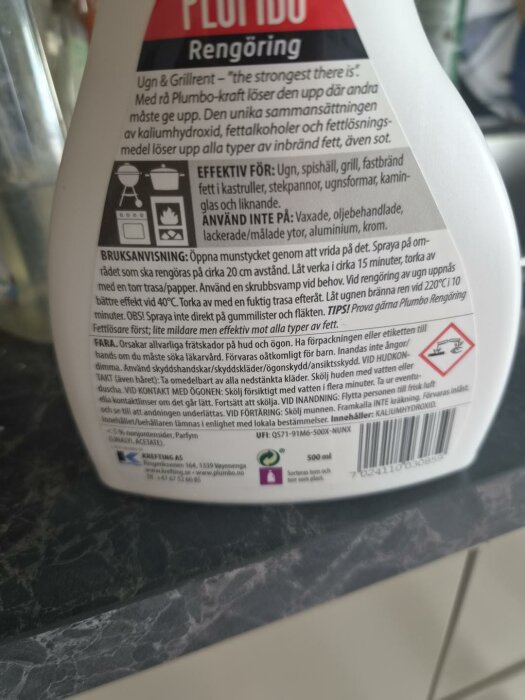 Närbild på etiketten av en flaska Plumbo rengöringsmedel. Texten beskriver produktens användningsområden och varningar.