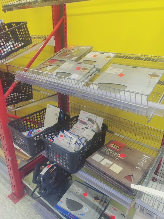 Hyllor med Bosch sågklingor, borrar och andra tillbehör i en butik, med varumärken och förpackningar synliga.