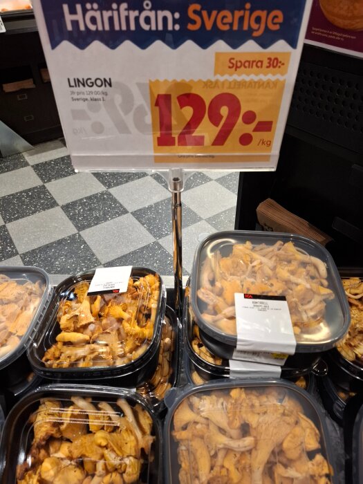 Plastförpackningar med kantareller uppställda i en butik med en skylt som visar priset 129 kr/kg och texten "Härifrån: Sverige".