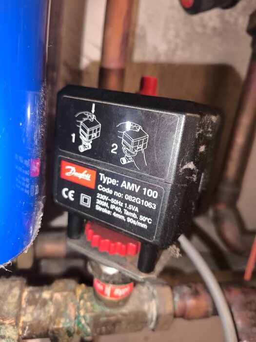 Elektrisk ventiltyp AMV 100 från Danfoss monterad på rörledning, visar instruktioner för manuell justering.