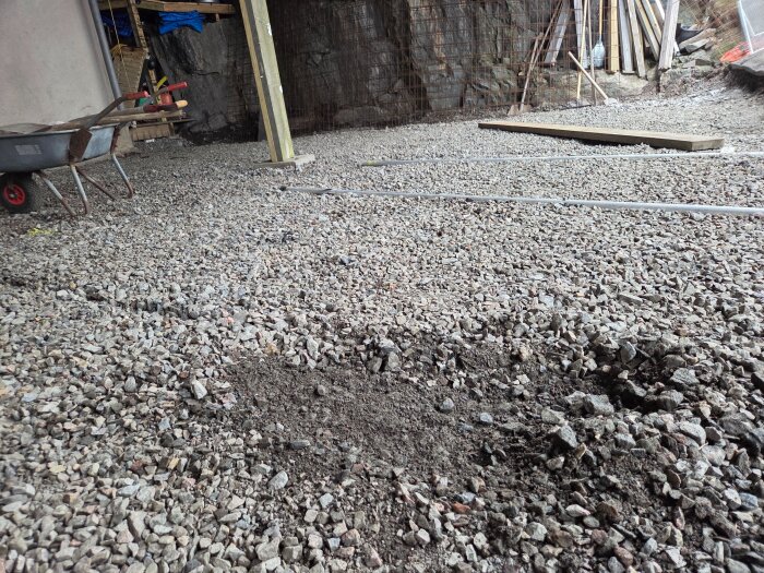 Grus- och markberedning inför gjutning av garageplatta, med skottkärra och verktyg i bakgrunden.