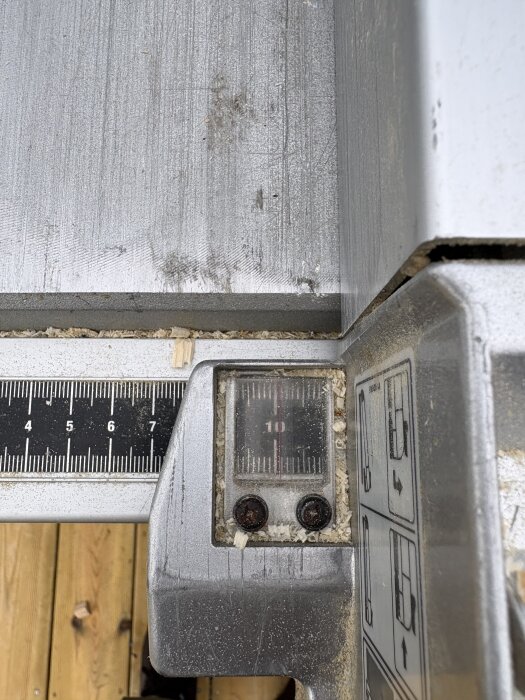 Klyvsåg 2704 med mätverktyg inställt på 10 mm, visar felaktig justering med sågspån och brädgolv i bakgrunden.