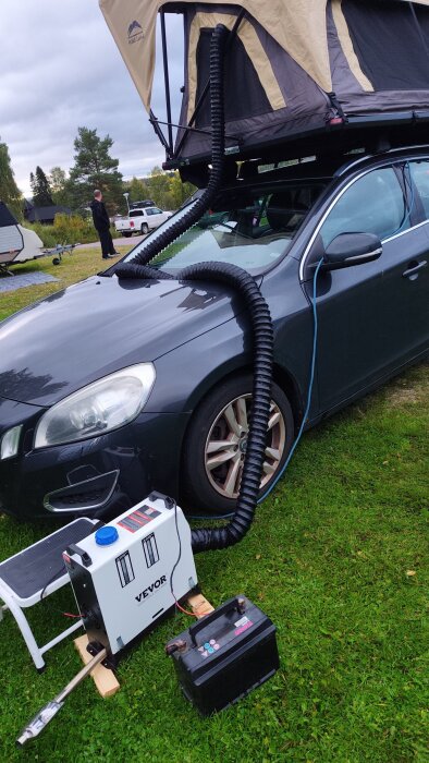 Bil med taktält och inkopplad dieselvärmare på plats, utomhus på gräsmatta.