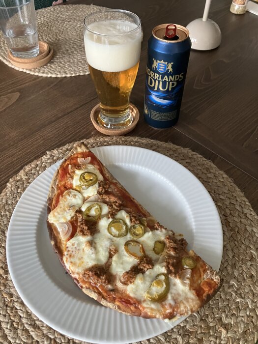 Pizza på hönökaka med tomatsås, lök, köttfärssås, mozzarella och jalapeños, serverad med ett glas öl och en burk Norrlands Djup.