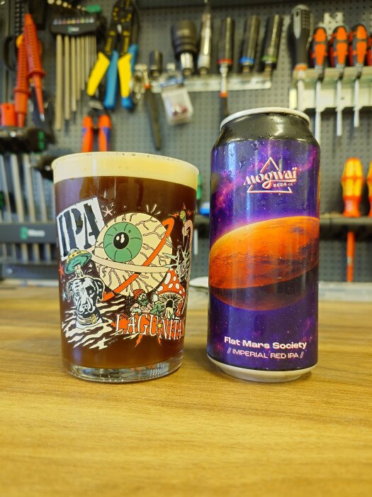 Ett glas med röd IPA från Lagunitas och en burk Flat Mars Society Imperial Red IPA på ett bord med verktyg i bakgrunden.