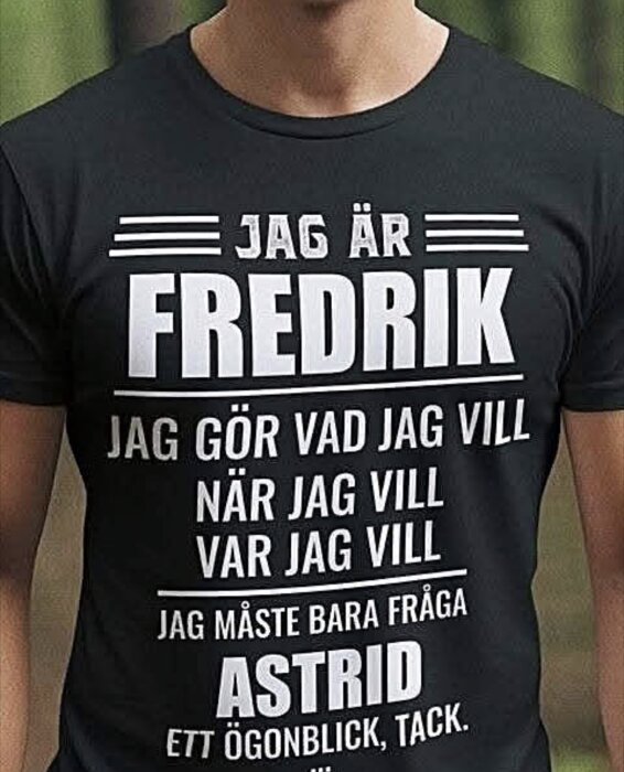 Person i svart t-shirt med texten: "Jag är Fredrik. Jag gör vad jag vill när jag vill var jag vill. Jag måste bara fråga Astrid ett ögonblick, tack.