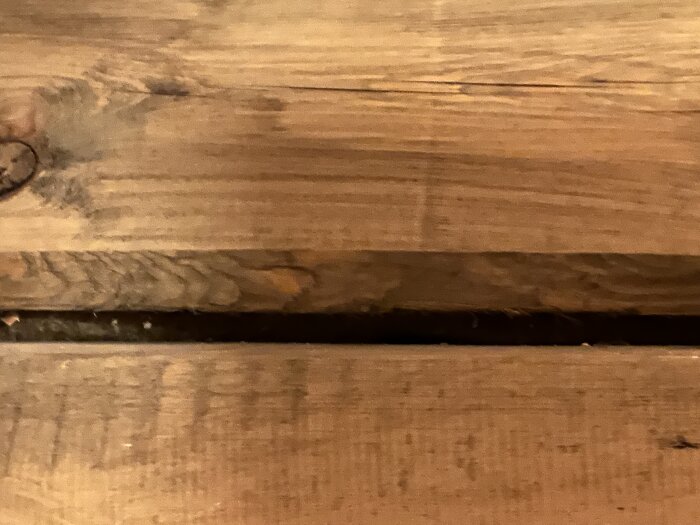Närbild på vridet och sprucket timmer i ett nybyggt hus, synligt mellanrum mellan plankorna.