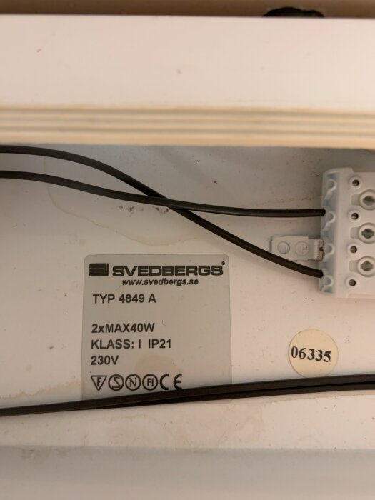 Skylt med information om elektrisk anslutning för lampa, märkt Svedbergs, med specifikationer 2xMAX40W, Klass I IP21, 230V.