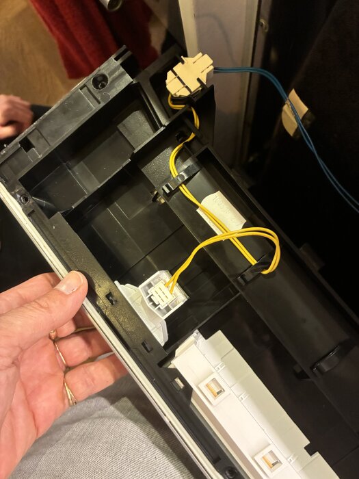 Närbild av interiören på en Siemens apparat med exponerade kablar och anslutningar, fokus på en potentiellt trasig kontakt eller knapp.