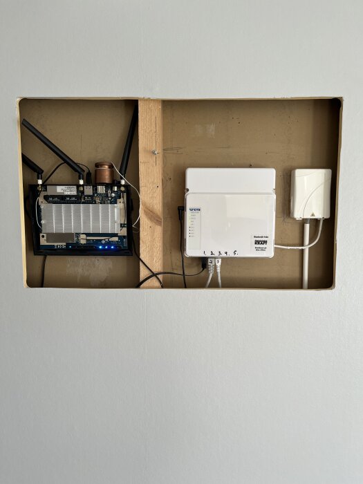 Inbyggd router i väggen utan lock för bättre kylning, med tavla ovanför för ventilation, fungerat väl i flera år.
