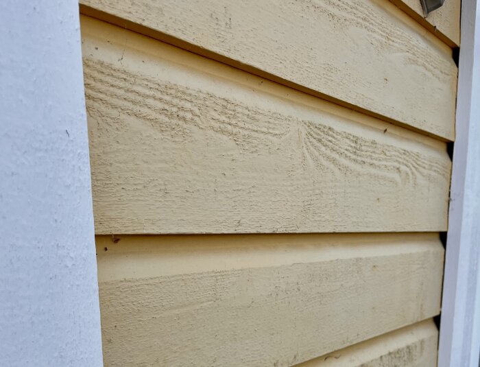 Beige träpanel med slät yta och en lätt sluttande sektion mot fasaden, visas från sidan.