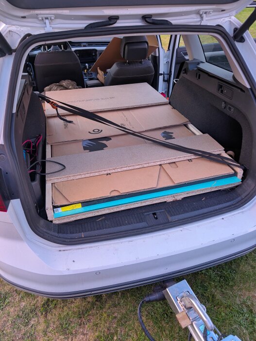 Glas transporterade i bilens baklucka, packade med kartong och golvspånskivor, säkrade med remmar för att skydda under transport.