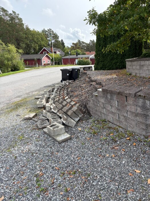 Stödmur i villaområde har rasat, stenblock ligger på marken.